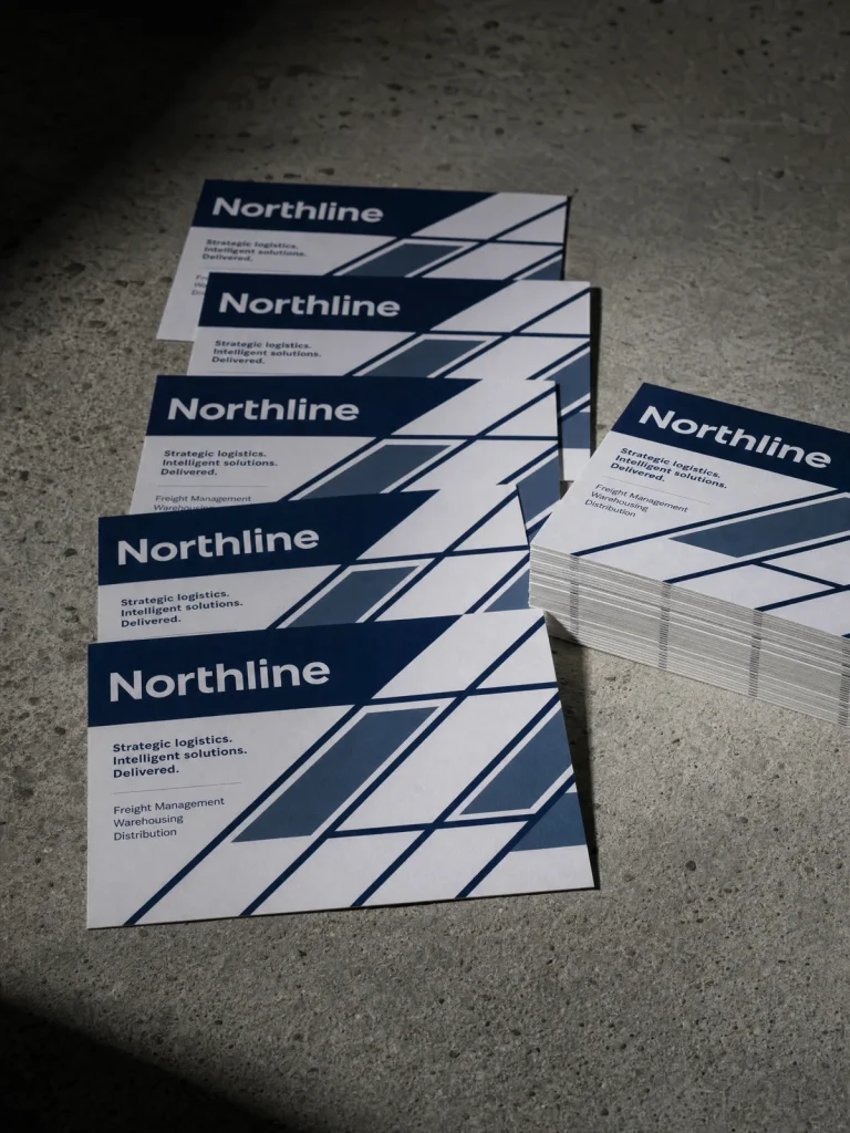 A6 postcards with navy Northline service branding and geometric artwork, arranged with a stack of cards.